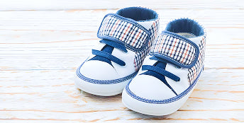 Pair of baby shoes with blue and white design on a wooden surface