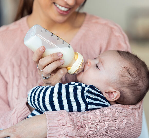 Woman feeding a baby from a bottle with a blurred background
