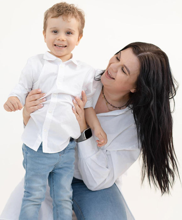 Woman holding a child wearing a white shirt and blue jeans